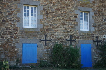 Fototapeta na wymiar old stone house with window and blue shutters in brittany france