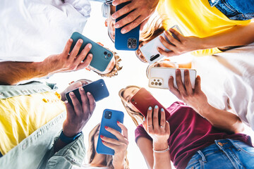 Teens in circle holding smart mobile phones - Multicultural young people using cellphones outside - Teenagers addicted to new technology concept - 529650232