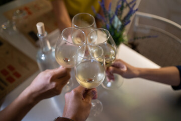 Hand holding wine glass toasting with white wine for celebration in blur background