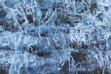 Texture of winter ice on a stone cliff. Blue natural ice background