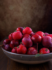 Full plate of fresh red apples on a wooden table. Side view.