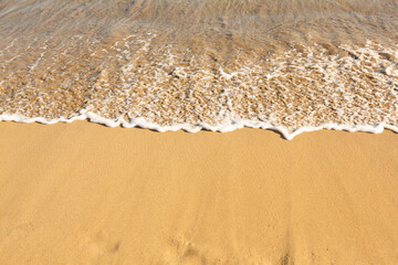 Background with golden sand on the coast of the island of Crete. Abstract surface with sand and clear sea water for text.