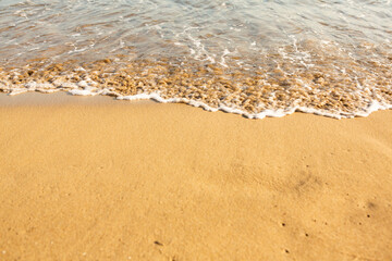Background with golden sand on the coast of the island of Crete. Abstract surface with sand and clear sea water for text.