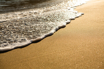 Background with golden sand on the coast of the island of Crete. Abstract surface with sand and clear sea water for text.