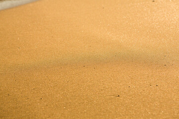 Background with golden sand on the coast of the island of Crete. Abstract surface with sand and clear sea water for text.