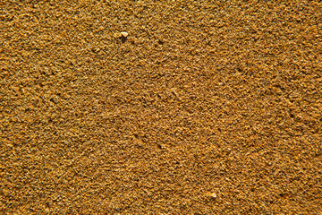 Background with golden sand on the coast of the island of Crete. Abstract surface with sand and clear sea water for text.