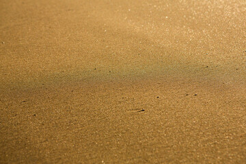 Background with golden sand on the coast of the island of Crete. Abstract surface with sand and clear sea water for text.