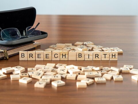 Breech Birth Word Or Concept Represented By Wooden Letter Tiles On A Wooden Table With Glasses And A Book