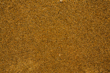 Background with golden sand on the coast of the island of Crete. Abstract surface with sand and clear sea water for text.
