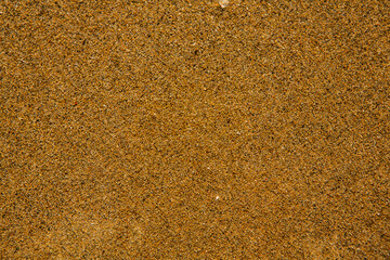 Background with golden sand on the coast of the island of Crete. Abstract surface with sand and clear sea water for text.