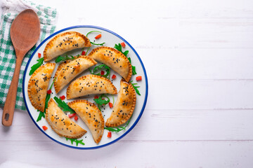 Argentine empanadas handmade with traditional recipe. Aerial shot decorated with red pepper and arugula.