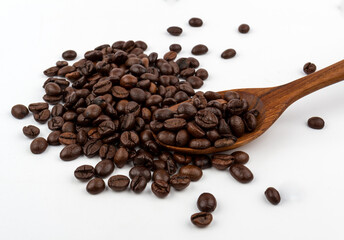 Roasted coffee beans in wood spoon on white background.