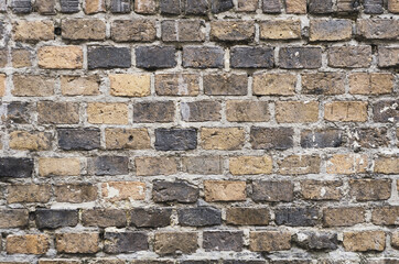 Faded old red brick wall, wide rough vintage texture. Dirty wall with grunge rectangular blocks, close-up, grungy texture of blackened bricks.