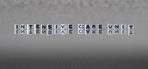 intensive care unit word or concept represented by black and white letter cubes on a grey horizon...