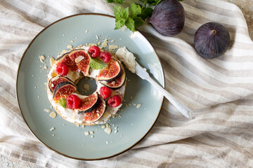 plate with bagel with cheese, figs and raspberries on the table