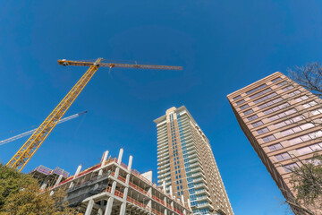 Fototapeta na wymiar Modern residential buildings and construction crane against vibrant blue sky