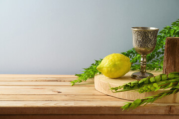 Jewish holiday Sukkot celebration background with traditional symbols and decorations on wooden...