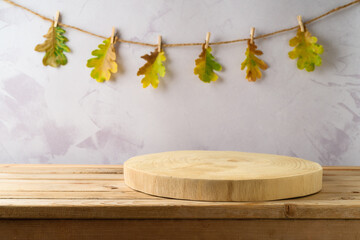 Empty wooden log on table over autumn leaves garland background. Autumn kitchen mock up for design...