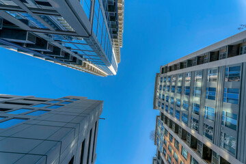 Fototapeta na wymiar Modern apartments with sunlit exterior against vibrant blue sky on a sunny day