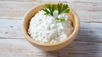 Cottage cheese in a bowl  on a wooden background. Diet and healthy eating concept