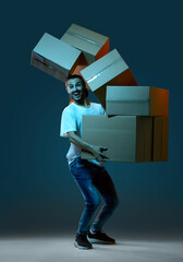 Emotional delivery guy with a lot of boxes on a dark blue background