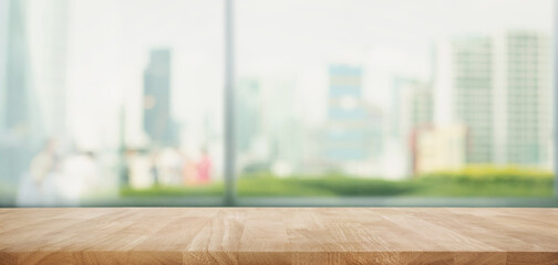 Selective focus.Top of wood  table with window glass and cityscape background.