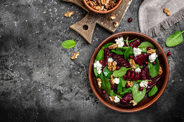 Obraz na płótnie Canvas Healthy Beet Salad with fresh sweet baby spinach, cheese, nuts, cranberries on a dark background. place for text, top view