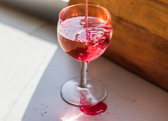 Shot of a red liquid being poured in to the wine glass. Concept
