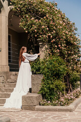 Obraz premium a beautiful woman in a white flowing long dress stay near a beautiful field with pink flowers rear view