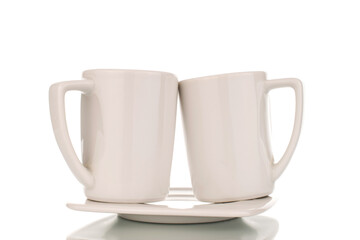 Two white ceramic coffee cups on a saucer, close-up, isolated on a white background.