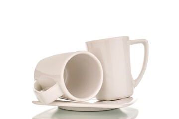Two white ceramic coffee cups on a saucer, close-up, isolated on a white background.