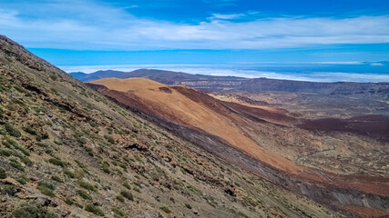 Scenic view from summit of volcano Pico del Teide over the island of Tenerife, Canary Islands, Spain, Europe. Vista on barren landscape, solidified lava, ash, pumice. Valley and sea covered in clouds
