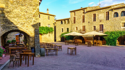 Central Square of the medieval village of Monells with its stone houses and arches in the buildings, Girona, Spain.