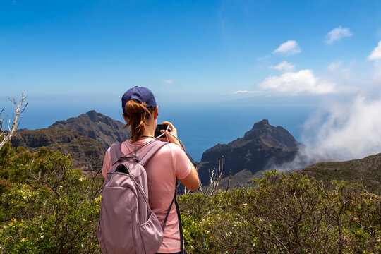 Woman taking picture of sharp rock formation Roque de la Fortaleza and Pico Yeje in Teno mountain massif, Tenerife, Canary Islands, Spain, Europe. Hiking trail between Masca and Santiago del Teide