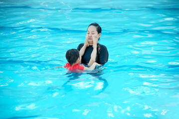 Little asian boy playing with his mother in swimming pool