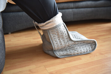 A woman warms her feet on a cold winter day. Expensive heating costs in the cold season.