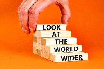 Look at the world wider symbol. Concept words Look at the world wider on wooden blocks on a beautiful orange background. Businessman hand. Business and look at the world wider concept. Copy space.