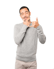 Hesitant young man making a gesture of calling with the hand