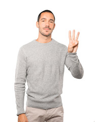 Young man making a number three gesture