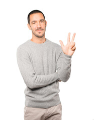 Fototapeta premium Young man making a number three gesture