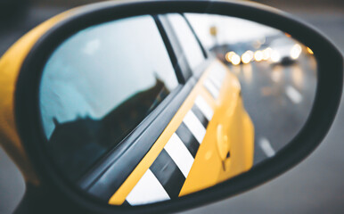 side rear-view mirror of a yellow taxi cab car
