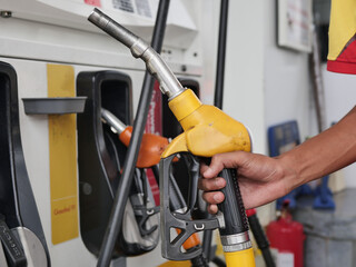 man hand holding a green gas nozzle. A man's hand is pulling the fuel dispenser out of the red...