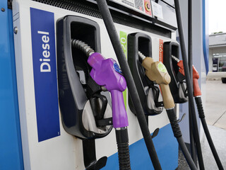 gas pump nozzles at gas . man hand holding a green gas nozzle. A man's hand is pulling the fuel...