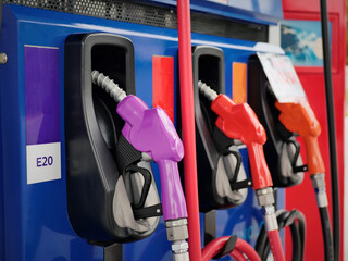 man hand holding a green gas nozzle. A man's hand is pulling the fuel dispenser out of the red...