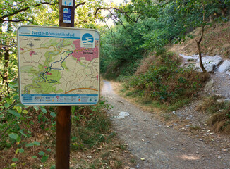 Schild vom Wanderweg Traumpfädchen Nette Romantikpfad neben einem schmalen Pfad im Wald bei Ochtendung im Landkreis Mayen-Koblenz, Rheinland-Pfalz.