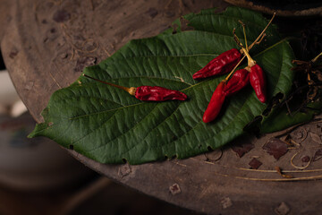 Dried red chilies on a leaf used for cooking shot in low light
