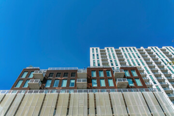 Looking up at modern luxury apartment against vibrant cloudless blue sky