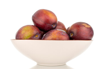 Several juicy plums on a ceramic white plate, macro, isolated on a white background.