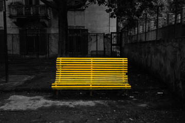 Old yellow park bench against bullying and cyberbullying. Ruined and rusty bench surrounded by...