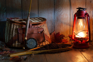 Vintage fly fishing rod creel and net with lantern on old wood background - obrazy, fototapety, plakaty